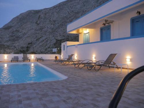 a villa with a swimming pool in front of a building at Ancient Thera Apartments in Kamari