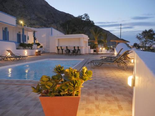 a pool with a potted plant next to a building at Ancient Thera Apartments in Kamari