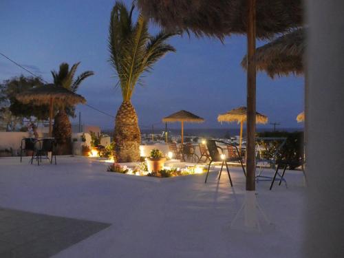a group of tables and umbrellas on the beach at night at Ancient Thera Apartments in Kamari