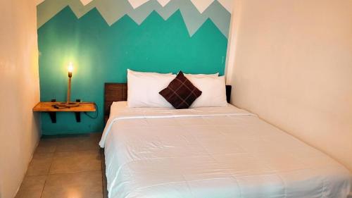 a bedroom with a white bed with a green wall at Hotel Montañita in Montañita