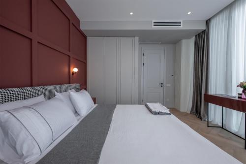 1 dormitorio con 1 cama blanca grande y pared roja en Metekhi Elegance-Classic Charm in Tbilisi's Heart, en Tiflis