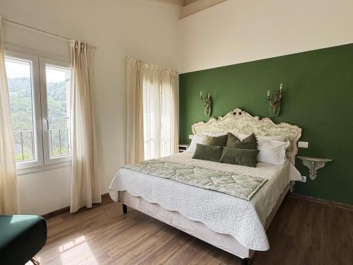 a bedroom with a large bed with a green wall at La Valle degli Amici in Pianello Val Tidone