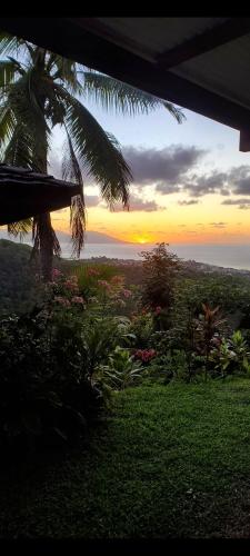 a view of the sunset from a house with a palm tree at Fare Bungalow in Papeete