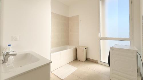 La salle de bains blanche est pourvue d'un lavabo et d'une baignoire. dans l'établissement Meilleure vue de Bordeaux, à Bordeaux