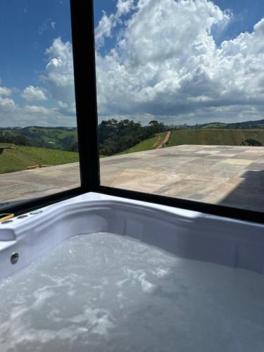 a bath tub in front of a window with a view at Casa de Vidro na Montanha in Cambuí