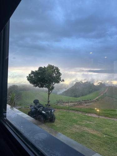 a motorcycle parked next to a window with a tree at Casa de Vidro na Montanha in Cambuí