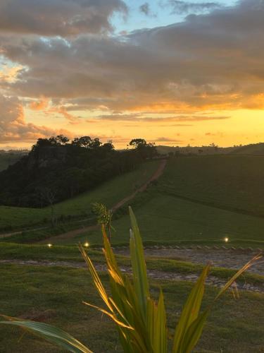 a sunset over a field with a dirt road at Casa de Vidro na Montanha in Cambuí