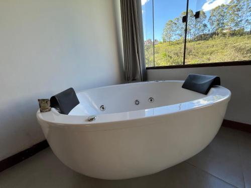 a white bath tub in a room with a window at Chalé Lírio do Campo in Lavras Novas
