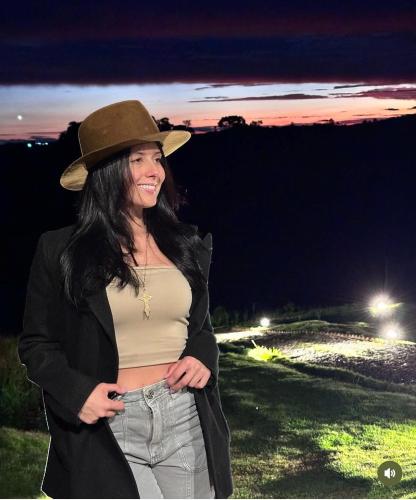 a woman wearing a hat standing in a field at Casa de Vidro na Montanha in Cambuí