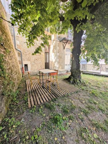 une table posée sur un banc sous un arbre dans l'établissement Maison Marguerite, à Loches