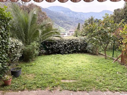 un jardin avec de l'herbe, des arbres et des montagnes en arrière-plan dans l'établissement La renaissance au calme, à Gorbio