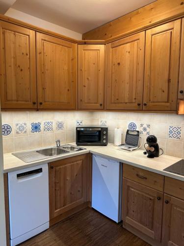 a kitchen with wooden cabinets and a sink and a microwave at Apartments Vršič on the ski slope with free parking in Kranjska Gora