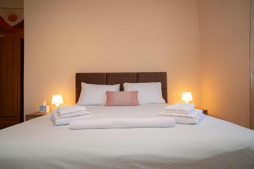 a bed with white sheets and pillows and two lamps at TheaHouse in Pythagoreio