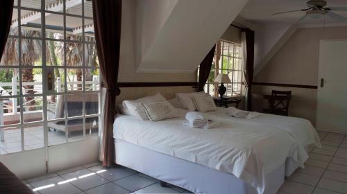 a bedroom with a bed with white sheets and windows at Summerview Guest Lodge in Johannesburg