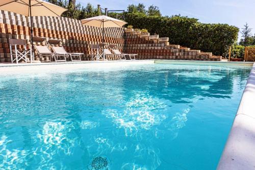 a large swimming pool with chairs and umbrellas at Villa Lucilla - B&B Rooms and Pool in Potenza Picena