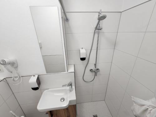 a white bathroom with a sink and a mirror at Aparthotel B & L in Bremen