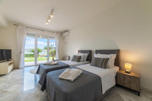 ein Schlafzimmer mit zwei Betten und einem Fernseher und einem Fenster in der Unterkunft Villa Blue Horizon in Kalívia Thorikoú