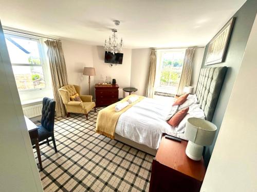 Un dormitorio con una cama y una silla y ventanas. en John Martin Room, en Haydon Bridge