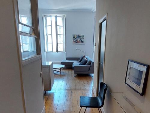 un salon avec un canapé et une chaise dans l'établissement Burdigala Homes - Appart rue Ausone, à Bordeaux