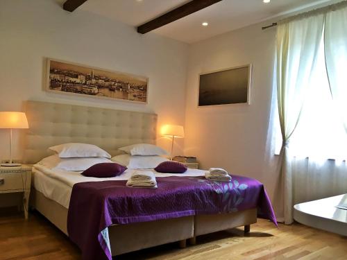 Cette chambre comprend un lit avec des draps violets et une baignoire. dans l'établissement Magnolia Luxury Apartments, à Split