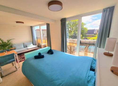 a bedroom with a blue bed and a balcony at Welkom Op Texel privé kamer op het zuiden in De Koog