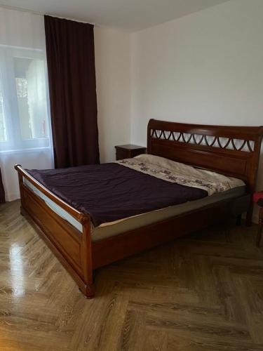 a wooden bed in a bedroom with a wooden floor at Wind Mood in Klebiškis
