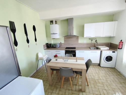 une cuisine avec une table et des chaises dans une cuisine dans l'établissement Appartement climatisé avec terrasse 4 à 6 couchages à 600m du centre thermal, à Lamalou-les-Bains