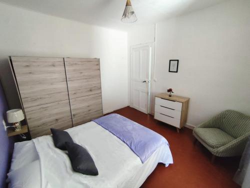 une chambre avec un grand lit et une chaise dans l'établissement Appartement climatisé avec terrasse 4 à 6 couchages à 600m du centre thermal, à Lamalou-les-Bains