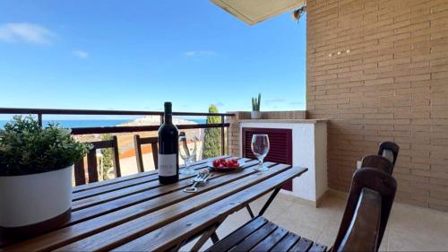 a wooden table with a bottle of wine on a balcony at Coral beach in Peñíscola