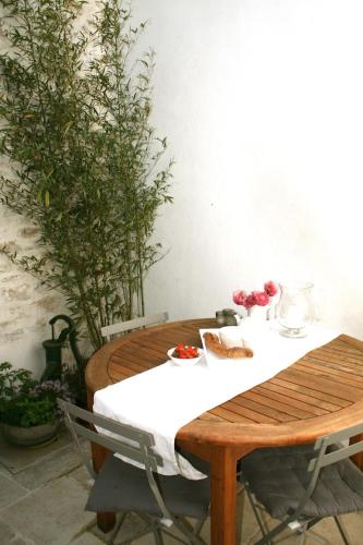 a wooden table with a white table cloth on it at Mamaisondouce in Saint-Clément-des-Baleines