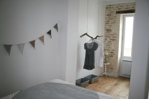 a bedroom with a black dress hanging on a wall at Mamaisondouce in Saint-Clément-des-Baleines