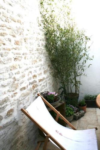a chair sitting next to a brick wall with potted plants at Mamaisondouce in Saint-Clément-des-Baleines