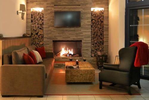 a living room with a fireplace with a couch and a chair at Wittenbeck Resort in Kühlungsborn