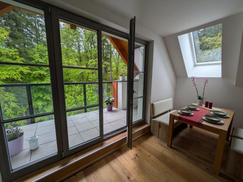 Un pequeño comedor con una mesa y grandes ventanales. en Apartmán A10 v centru Harrachova, en Harrachov