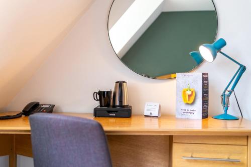 a desk with a lamp and a mirror on it at Holiday Inn Ashford - North A20 by IHG in Ashford