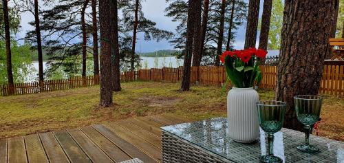 a white vase with red flowers sitting on a table at Domki LeMo - nad samym jeziorem, nowe w pełni wyposażone z miejscem parkingowym in Borsk