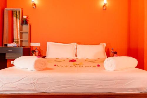 a bedroom with an orange wall and a white bed at SEASUNBEACH Maafushi in Maafushi