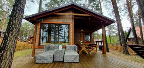 a cabin in the woods with a table and chairs at Domki LeMo - nad samym jeziorem, nowe w pełni wyposażone z miejscem parkingowym in Borsk