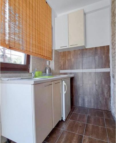 a kitchen with white cabinets and a tile wall at Olea apartments in Budva