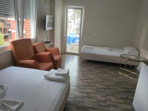 a room with two beds and a bed and chairs at Hotel Albani in Lezhë