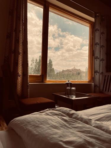 a bedroom with a bed and a large window at Zlatan Guest House in Leh