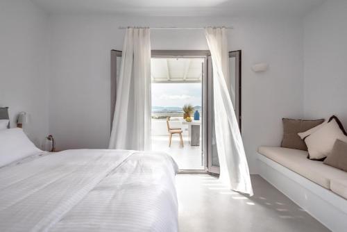 a white bedroom with a bed and a couch at Seven Suites in Glinado Naxos