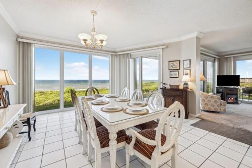 a dining room with a table and chairs with a view of the ocean at HP 16E Beach Treat by 30A Escapes in Rosemary Beach