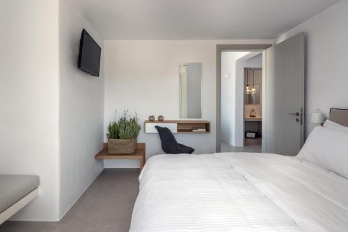 a white bedroom with a white bed and a tv at Seven Suites in Glinado Naxos