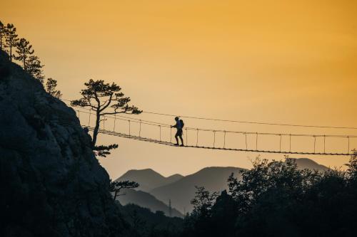 a man standing on a suspension bridge in the mountains at Kanjon 987 in Podgrad
