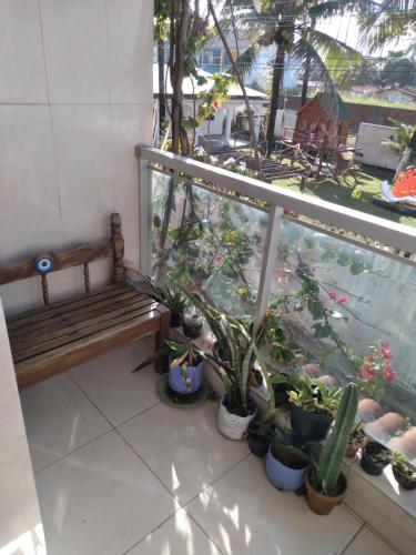 a balcony with a bench and a bunch of potted plants at Maracaípe Cantinho Vida Boa in Porto De Galinhas