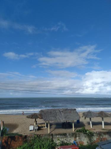 a beach with tables and umbrellas and the ocean at Maracaípe Cantinho Vida Boa in Porto De Galinhas