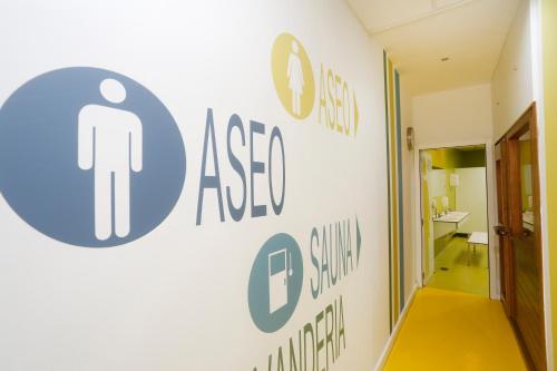 a hallway with a sign on the wall of a restroom at Albergue Spa Cruceiro de Pedrouzo in O Pedrouzo