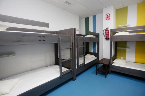 a room with three bunk beds with a fire extinguisher at Albergue Spa Cruceiro de Pedrouzo in O Pedrouzo