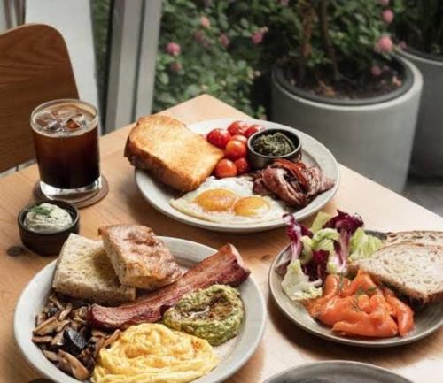zwei Teller mit Frühstücksspeisen auf einem Holztisch in der Unterkunft as suite guest huseT2 in Mumbai